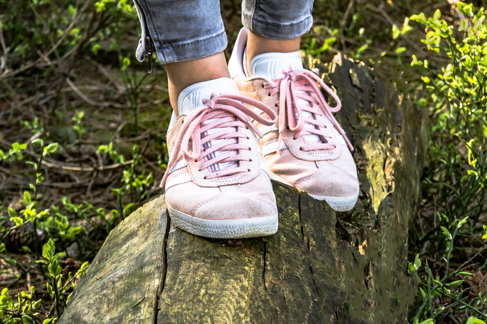 Picture of lower legs of woman balancing on a log wearing sneakers